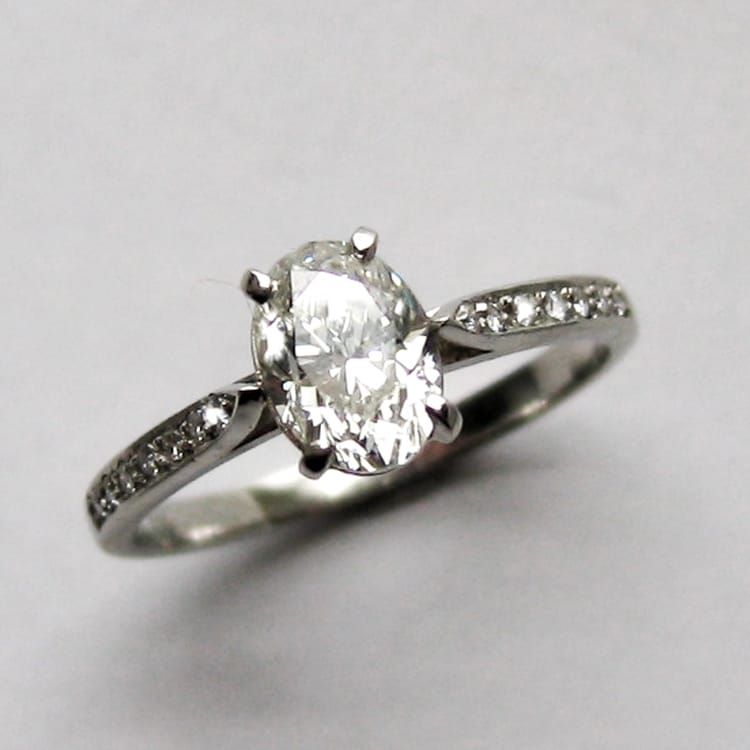 A Single Stone Oval Diamond Ring With Diamond Shoulders
